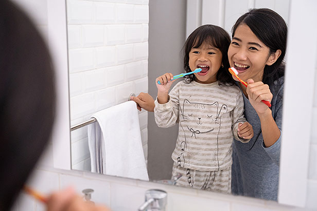 Mother and daughter brushing together using kid's toothpaste