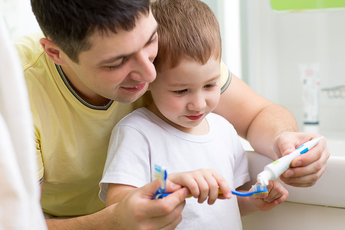 Dad teaches son to brush teeth using Orajel Kids anti cavity toothpaste