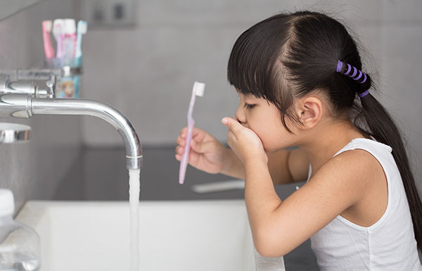 Child brushing her teeth with Orajel kids natural toothpaste