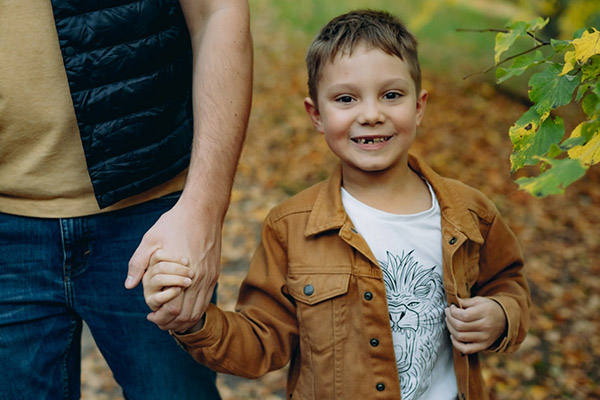 Little boy with missing tooth holding dad's hand